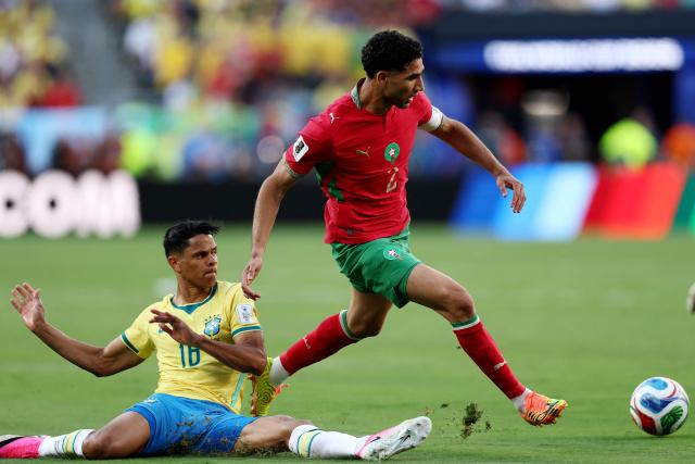 Brazil's defender #16 Douglas Santos falls on the ground past Morocco's defender #02 Achraf Hakimi during the 2026 World Cup Group C football match between Brazil and Morocco at the New York/New Jersey Stadium in East Rutherford on June 13, 2026. (Photo by CHARLY TRIBALLEAU / AFP)