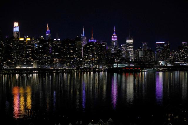 Multiple buildings in the New York City skyline including the Empire State Building are lit with the colors of New York Knicks after the New York Knicks defeated the San Antonio Spurs in Game 5 of the NBA Finals to win the series, as seen from West New York, New Jersey, on June 13, 2026. The Knicks won the NBA Championship for the first time since 1973, for the third time in franchise history. (Photo by Leonardo MUNOZ / AFP)