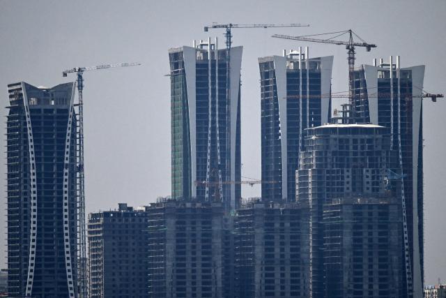 Cranes operate next to newly constructed high-rise buildings on the outskirts of Islamabad on June 14, 2026. Pakistan's government presented its annual budget on June 12, including plans to boost tax collection and defence spending, as citizens expressed weariness with surging inflation sparked by the Middle East crisis that Islamabad is mediating to end. (Photo by Aamir QURESHI / AFP)