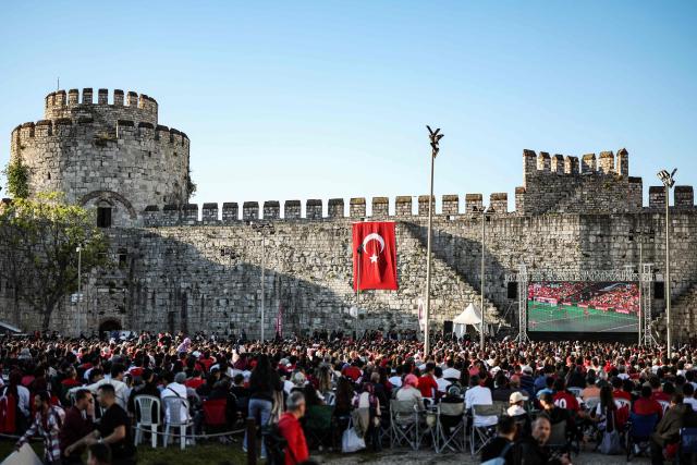 Turkish fans weaves Turkish national flags as they watch a broadcast of the FIFA World Cup 2026 Group D match between Australia and Turkey on a giant screen at the Yedikule fortress, which encloses a section of the ancient Walls of Constantinople, in Istanbul on June 14, 2026. (Photo by BERK OZKAN / AFP)