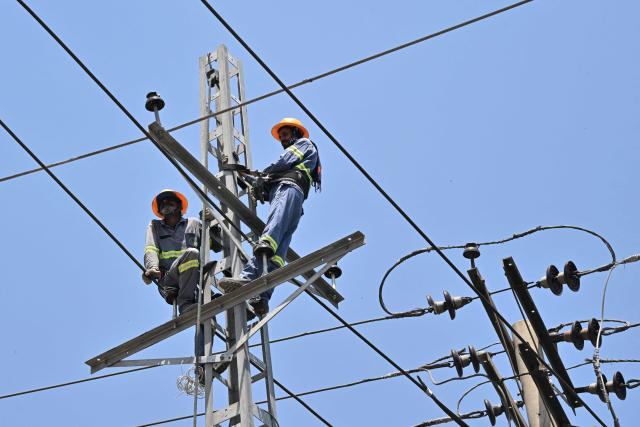Electricians work on high-voltage power lines in Lahore on June 14, 2026. (Photo by Arif ALI / AFP)