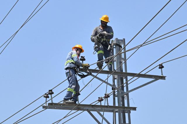 Electricians work on high-voltage power lines in Lahore on June 14, 2026. (Photo by Arif ALI / AFP)