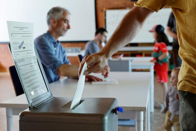 A citizen casts his ballot at a polling station in Bern, on June 14, 2026 as Swiss vote on a divisive anti-immigration proposal to cap the country's population and another referendum on restricting access to conscientious objection to military service. (Photo by STEFAN WERMUTH / AFP)