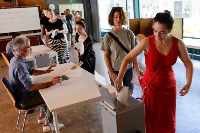 A citizen casts her ballot at a polling station in Bern, on June 14, 2026 as Swiss vote on a divisive anti-immigration proposal to cap the country's population and another referendum on restricting access to conscientious objection to military service. (Photo by STEFAN WERMUTH / AFP)