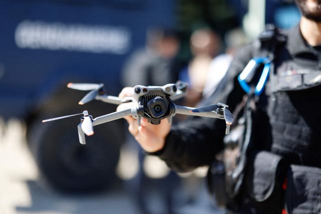 A gendarme belonging to the Armoured Mobile Gendarmerie Unit (GBGM) holds a drone during a dynamic demonstration of military equipment at the Eurosatory trade show, dedicated to defense and security, at the Paris Nord Villepinte Exhibition Center in Villepinte, northeastern suburb of Paris on June 14, 2026. The Eurosatory trade show takes place from June 15 to 19, 2026. (Photo by Kenzo TRIBOUILLARD / AFP)