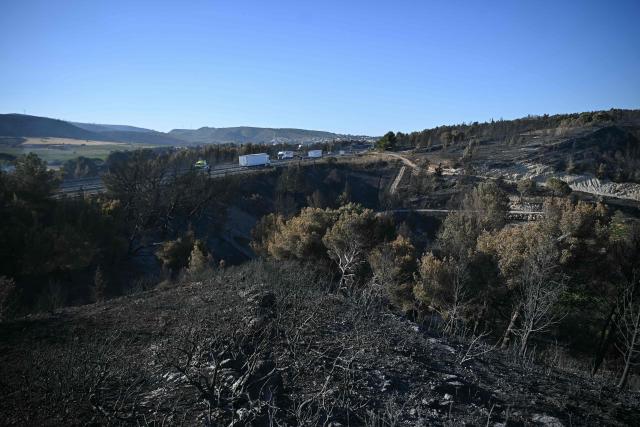 (FILES) This photographs shows scorched ground in the aftermath of a wildfire in the Prat de Cest near the city of Narbonne, southwestern France, on July 8, 2025. A trail race organized by three students from Narbonne, the "Trail des Cendres" (Ashes Trail), will take place on June 14, 2026, in Bages, in the Aude department to pay tribute to the area devastated by wildfires last summer. The area surrounding the village, south of Narbonne, was ravaged by the fire of July 7, 2025, which burned through more than 2,000 hectares of vegetation and whose scars are still visible almost a year later. (Photo by Matthieu RONDEL / AFP)