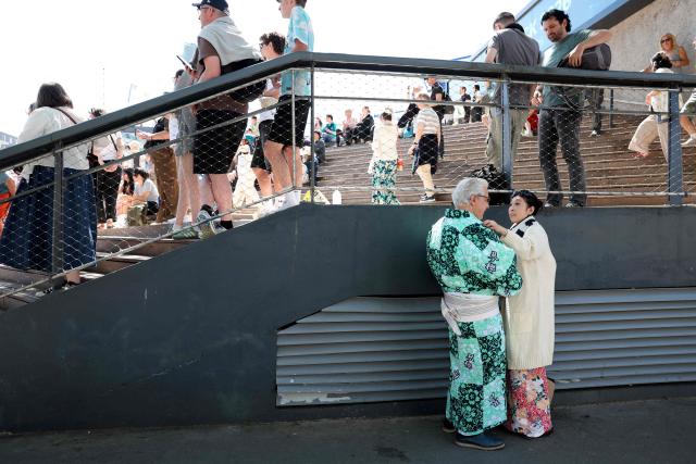 A couple, wearing a Yukata (L) and a Kimono (R), wait outside the Accor Arena on day 2 of the 2026 Paris Sumo Tournament, in Paris on June 14, 2026. (Photo by Behrouz MEHRI / AFP)