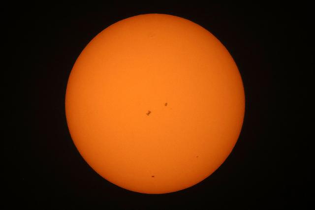 The International Space Station (ISS), (center-R) transits the sun as seen from Shuwaikh industrial  district in Kuwait City on June 14, 2026. (Photo by YASSER AL-ZAYYAT / AFP)