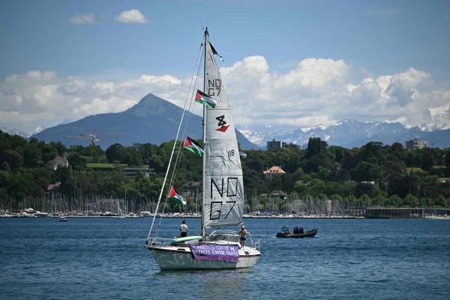 Demonstrators stand on a sailboat of the Global Sumud Flotilla with Palestinian flags and a banner reading "violence against one, violence against all, solidarity with Palestine" ahead of a demonstration of a "No-G7" coalition of over 60 associations, unions and left-wing groups "against fascism and imperialism, a day ahead of the event's start, in Geneva on June 14, 2026. The 2026 edition of the G7 summit is set to take place June 15 to 17 in the French town of Evian-les-Bains near Switzerland, attended by country leaders as well as the EU's foreign policy chief and ministers from Brazil, Canada, the United Arab Emirates and Turkey. (Photo by Fabrice COFFRINI / AFP)