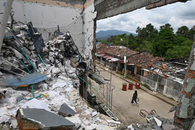 A woman walks past the Buenos Aires police station, months after it was heavily attacked, in Buenos Aires, Cauca department, Colombia, on June 13, 2026, Colombia will hold the runoff presidential election on June 21. (Photo by JOAQUIN SARMIENTO / AFP)