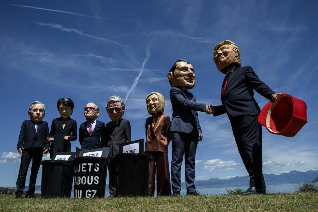 Demonstrators dressed up with caricature "big heads" representing the G7 heads of state (from L) Prime Minister of Canada Mark Carney, Prime Minister of Japan Sanae Takaichi, Chancellor of Germany Friedrich Merz, Prime Minister of the United Kingdom Keir Starmer, Prime Minister of Italy Giorgia Meloni, France's President Emmanuel Macron and US President Donald Trump, pose in front of mock trash cans with "human rights, "gender equality" and "climate" placards inside during a happening organised by the NGO OXFAM, in Publier eastern France, on June 14, 2026. A G7 summit is set to take place June 15 to 17 in the French town of Evian-les-Bains near Switzerland and it will be attended by country leaders as well as the EU's foreign policy chief and ministers from Brazil, Canada, the United Arab Emirates and Turkey. (Photo by JEFF PACHOUD / AFP)