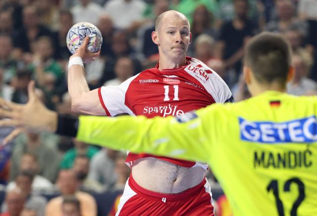 Aalborg's Danish pivot #11 Simon Hald Jensen (L) attempts to score past SC Magdeburg's Croatian goalkeeper Matej Mandic during the EHF Men's Handball Champions League Final 4 third place match between Aalborg Handbold and SC Magdeburg in Cologne, western Germany on June 14, 2026. (Photo by Ronny HARTMANN / AFP)