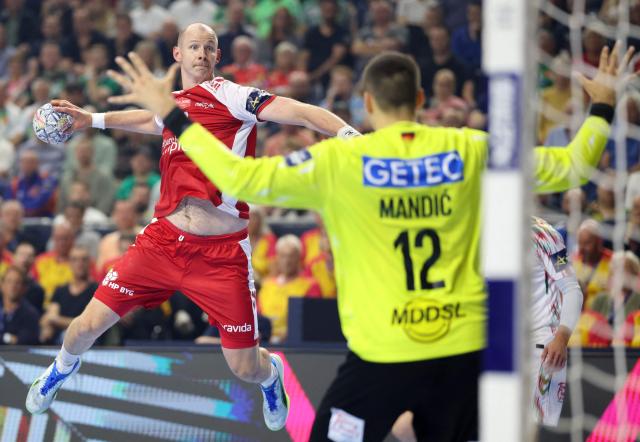 Aalborg's Danish pivot #11 Simon Hald Jensen (L) attempts to score past SC Magdeburg's Croatian goalkeeper Matej Mandic during the EHF Men's Handball Champions League Final 4 third place match between Aalborg Handbold and SC Magdeburg in Cologne, western Germany on June 14, 2026. (Photo by Ronny HARTMANN / AFP)