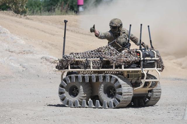 A soldier gestures next to a PROBOT mule robot during a dynamic demonstration of military equipment at the Eurosatory defence and security trade show at the Paris Nord Villepinte Exhibition Centre in Villepinte, a northeastern suburb of Paris, on June 14, 2026. The Eurosatory trade show takes place from June 15 to 19, 2026. (Photo by Kenzo TRIBOUILLARD / AFP)