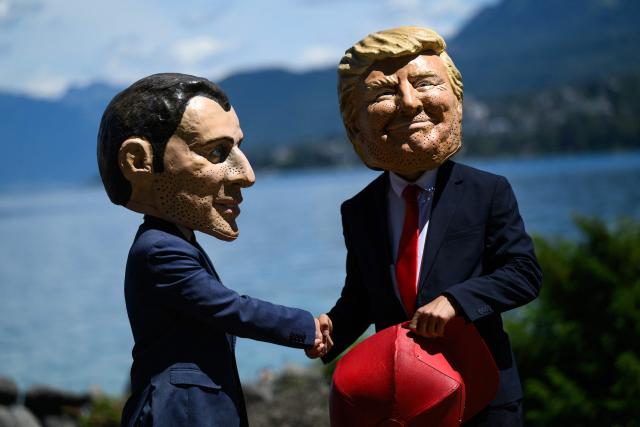 Demonstrators dressed up with caricature "big heads" representing the G7 heads of state France's President Emmanuel Macron and US President Donald Trump, pose in front of children during a happening organised by the NGO OXFAM, in Publier, eastern France on June 14, 2026. A G7 summit is set to take place June 15 to 17 in the French town of Evian-les-Bains near Switzerland and it will be attended by country leaders as well as the EU's foreign policy chief and ministers from Brazil, Canada, the United Arab Emirates and Turkey. (Photo by JEFF PACHOUD / AFP)