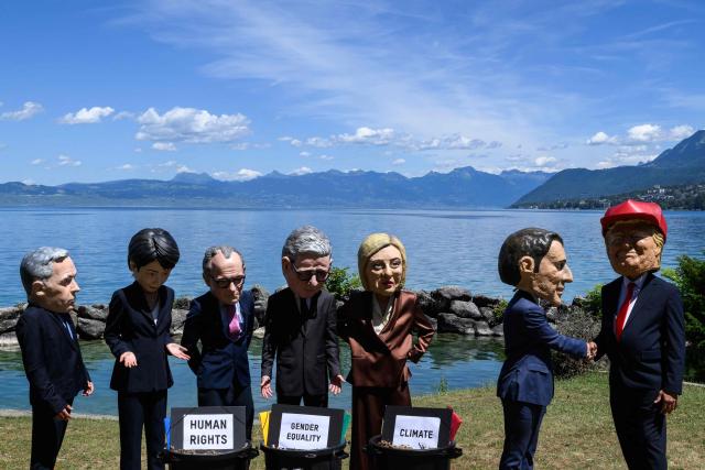 Demonstrators dressed up with caricature "big heads" representing the G7 heads of state (from L) Prime Minister of Canada Mark Carney, Prime Minister of Japan Sanae Takaichi, Chancellor of Germany Friedrich Merz, Prime Minister of the United Kingdom Keir Starmer, Prime Minister of Italy Giorgia Meloni, France's President Emmanuel Macron and US President Donald Trump, pose in front of mock trash cans with "human rights, "gender equality" and "climate" placards inside during a happening organised by the NGO OXFAM, in Publier eastern France, on June 14, 2026. A G7 summit is set to take place June 15 to 17 in the French town of Evian-les-Bains near Switzerland and it will be attended by country leaders as well as the EU's foreign policy chief and ministers from Brazil, Canada, the United Arab Emirates and Turkey. (Photo by JEFF PACHOUD / AFP)