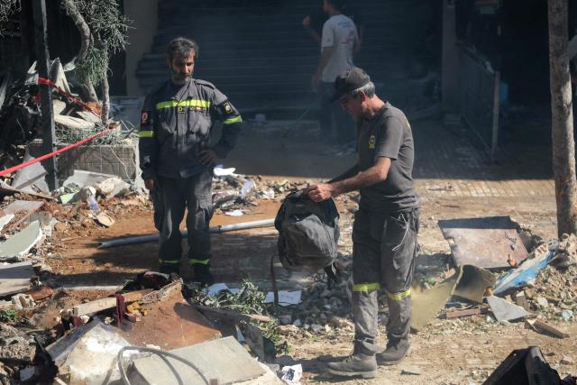 A first responder holds a backpack as people clear the rubble at the site of an Israeli airstrike that targeted a building in Beirut’s southern suburbs on June 14, 2026. The office of Israeli Prime Minister Benjamin Netanyahu said on June 14 the military had carried out strikes in Beirut's southern suburbs, known as Dahiyeh, while Lebanese state media said a strike hit the Ghobeiry neighbourhood. A senior Iranian military official warned that Israel's strike would not go "unanswered" by Tehran, according to local media. (Photo by Ibrahim AMRO / AFP) / 