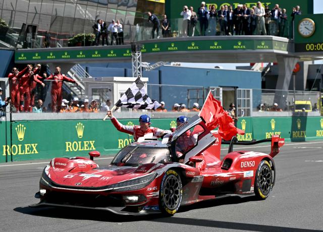 British driver Mike Conway, Japanese driver Kamui Kobayashi and Dutch driver Nyck de Vries celebrate on their Toyota #7 after winning the 94th edition of the 24 Hours of Le Mans at the Le Mans circuit, north-western France, on June 14, 2026. (Photo by LOU BENOIST / AFP)