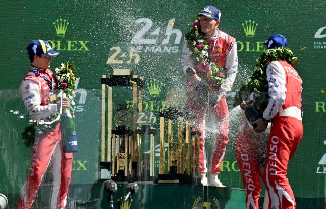The Toyota #7 drivers British Mike Conway, Japanese Kamui Kobayashi and Dutch Nyck de Vries celebrate on the podium after winning the 94th edition of the 24 Hours of Le Mans at the Le Mans circuit, north-western France, on June 14, 2026. (Photo by LOU BENOIST / AFP)