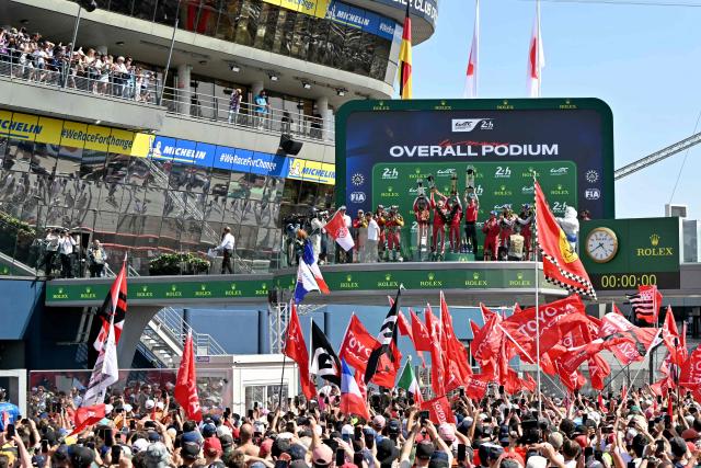 The Toyota #7 drivers British Mike Conway, Japanese Kamui Kobayashi and Dutch Nyck de Vries celebrate on the podium after winning the 94th edition of the 24 Hours of Le Mans at the Le Mans circuit, north-western France, on June 14, 2026. (Photo by LOU BENOIST / AFP)