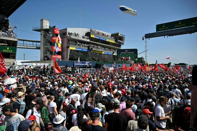 People gather on the track during the podium ceremony of the 94th edition of the 24 Hours of Le Mans at the Le Mans circuit, north-western France, on June 14, 2026. (Photo by LOU BENOIST / AFP)