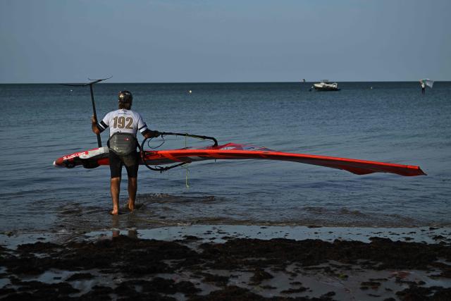French windsurfer and 27-times world champion Antoine Albeau carries his windsurf into the sea ahead of the start of the 4th edition of the Antoine Albeau Series off La Couarde-sur-Mer on the Ré island, southwestern France on June 14, 2026. (Photo by Christophe ARCHAMBAULT / AFP)