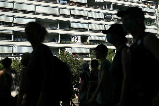 Demonstrators walk past a banner reading "NO G7" on a residential building facade during a rally of a "No-G7" coalition of over 60 associations, unions and left-wing groups "against fascism and imperialism, a day ahead of the summit's start, in Geneva on June 14, 2026. The 2026 edition of the G7 summit is set to take place June 15 to 17 in the French town of Evian-les-Bains near Switzerland, attended by country leaders as well as the EU's foreign policy chief and ministers from Brazil, Canada, the United Arab Emirates and Turkey. (Photo by Fabrice COFFRINI / AFP)