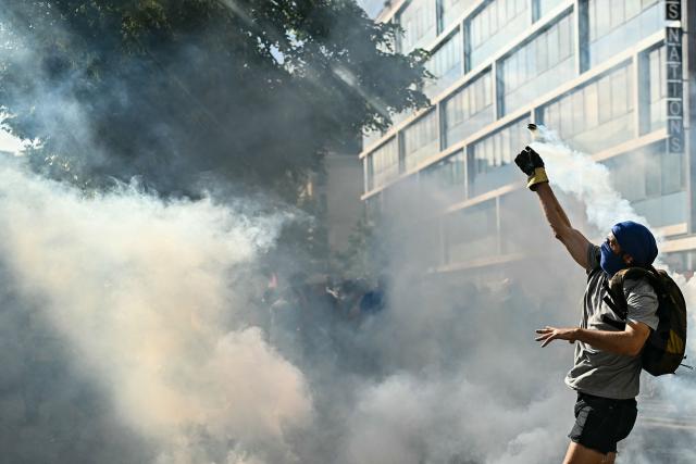 A demonstrator throws a fuming tear gas pellet during a rally of a "No-G7" coalition of over 60 associations, unions and left-wing groups "against fascism and imperialism, a day ahead of the summit's start, in Geneva on June 14, 2026. The 2026 edition of the G7 summit is set to take place June 15 to 17 in the French town of Evian-les-Bains near Switzerland, attended by country leaders as well as the EU's foreign policy chief and ministers from Brazil, Canada, the United Arab Emirates and Turkey. (Photo by Fabrice COFFRINI / AFP)
