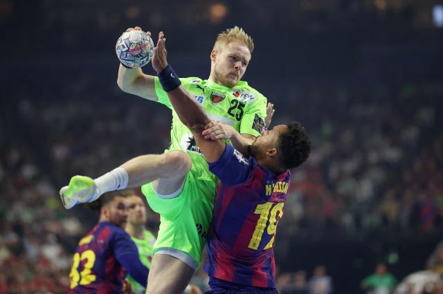 Fuechse Berlin's German left back Matthes Langhoff attempts to score past FC Barcelona's French left back #19 Timothey N'Guessan during the EHF Men's Handball Champions League Final 4 final between Barca and Fuechse Berlin in Cologne, western Germany on June 14, 2026. (Photo by Ronny HARTMANN / AFP)