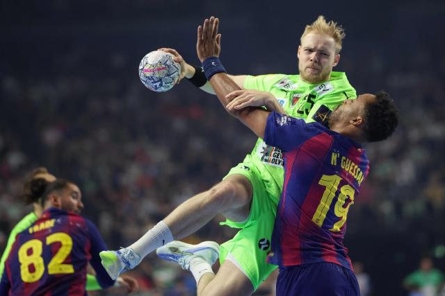 Fuechse Berlin's German left back Matthes Langhoff attempts to score past FC Barcelona's French left back #19 Timothey N'Guessan during the EHF Men's Handball Champions League Final 4 final between Barca and Fuechse Berlin in Cologne, western Germany on June 14, 2026. (Photo by Ronny HARTMANN / AFP)