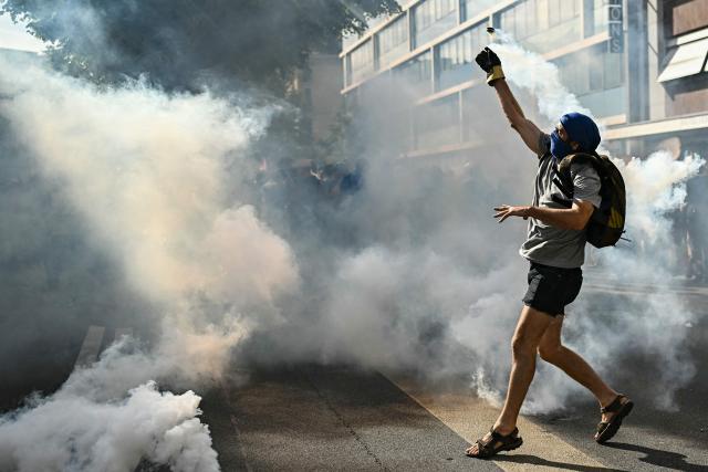 A demonstrator throws a fuming tear gas pellet during a rally of a "No-G7" coalition of over 60 associations, unions and left-wing groups "against fascism and imperialism, a day ahead of the summit's start, in Geneva on June 14, 2026. The 2026 edition of the G7 summit is set to take place June 15 to 17 in the French town of Evian-les-Bains near Switzerland, attended by country leaders as well as the EU's foreign policy chief and ministers from Brazil, Canada, the United Arab Emirates and Turkey. (Photo by Fabrice COFFRINI / AFP)