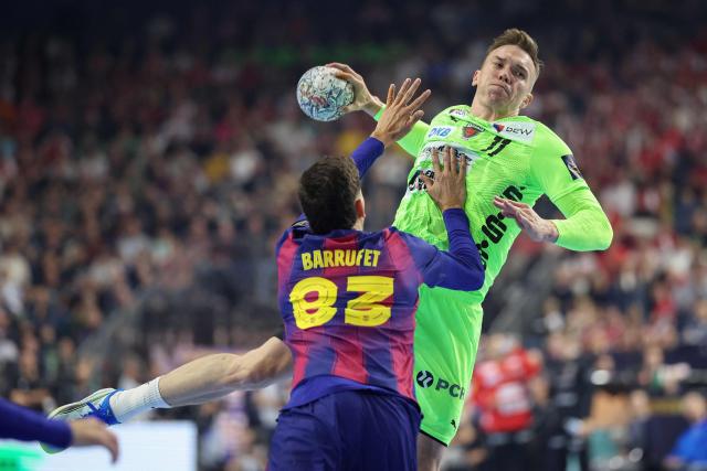 Fuechse Berlin's Danish left back Lasse Andersson jumps to shoot past FC Barcelona's Spanish left wing #83 Ian Barrufet vie for the ball during the EHF Men's Handball Champions League Final 4 final between Barca and Fuechse Berlin in Cologne, western Germany on June 14, 2026. (Photo by Ronny HARTMANN / AFP)