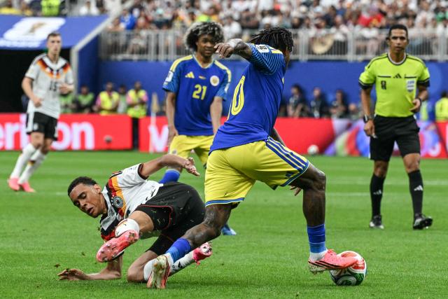 Germany's midfielder #10 Jamal Musiala (L) fights for the ball with Curacao's midfielder #10 Leandro Bacuna (C)  during the 2026 World Cup Group E football match between Germany and Curacao at the Houston Stadium in Houston on June 14, 2026.  (Photo by RONALDO SCHEMIDT / AFP)