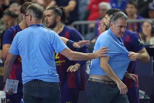 FC Barcelona's Spanish headcoach Antonio Carlos Ortega Perez (R) is calmed down by his players during the EHF Men's Handball Champions League Final 4 final between Barca and Fuechse Berlin in Cologne, western Germany on June 14, 2026. (Photo by Ronny HARTMANN / AFP)