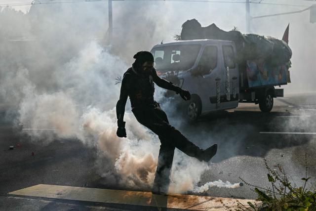 A demonstrator kicks a fuming tear gas pellet during a rally of a "No-G7" coalition of over 60 associations, unions and left-wing groups "against fascism and imperialism, a day ahead of the summit's start, in Geneva on June 14, 2026. The 2026 edition of the G7 summit is set to take place June 15 to 17 in the French town of Evian-les-Bains near Switzerland, attended by country leaders as well as the EU's foreign policy chief and ministers from Brazil, Canada, the United Arab Emirates and Turkey. (Photo by Fabrice COFFRINI / AFP)