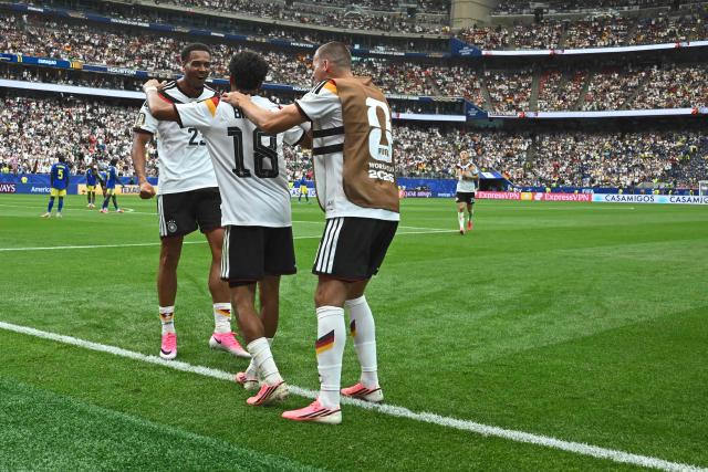 Germany's defender #18 Nathaniel Brown (C) is congratulated by Germany's defender #23 Felix Nmecha (L) after scoring a goal during the 2026 World Cup Group E football match between Germany and Curacao at the Houston Stadium in Houston on June 14, 2026.  (Photo by Paul ELLIS / AFP)
