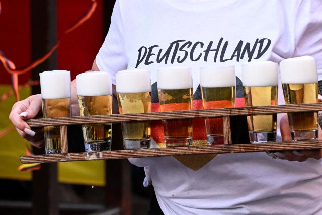 A waitress carries glasses of beer for German football fans follow the 2026 World Cup Group E football match between Germany and Curacao at a cafe in central Frankfurt am Main, western Germany on June 14, 2026.  (Photo by Kirill KUDRYAVTSEV / AFP)