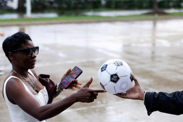 An Organized Power In Numbers (OPIN) staff member distributes soccer balls with “ICE OUT” messages outside of Houston Stadium in Houston, Texas, on June 14, 2026 before the 2026 World Cup Group E football match between Germany and Curacao. (Photo by Mark Felix / AFP)