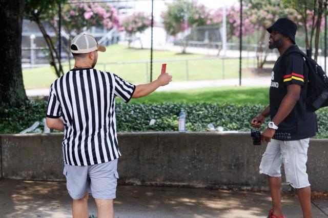 An Organized Power In Numbers (OPIN) staff member distributes "red cards" outlining constitutional rights outside Houston Stadium in Houston, Texas, on June 14, 2026. (Photo by Mark Felix / AFP)