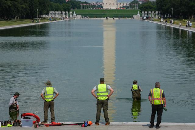 National Park Service workers push algae towards an aeration area in the center of the Lincoln Memorial Reflecting Pool following the completion of recent renovations in Washington, DC, on June 14, 2026. The reflecting pool project, undertaken as part of President Donald Trump’s preparations for the nation’s 250th anniversary, began in April and was completed last week. (Photo by Patrick T. Fallon / AFP)