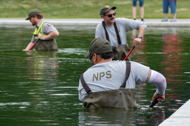National Park Service workers push algae towards an aeration area in the center of the Lincoln Memorial Reflecting Pool following the completion of recent renovations in Washington, DC, on June 14, 2026. The reflecting pool project, undertaken as part of President Donald Trump’s preparations for the nation’s 250th anniversary, began in April and was completed last week. (Photo by Ken CEDENO / AFP)