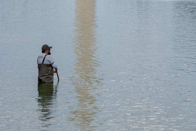 National Park Service workers push algae towards an aeration area in the center of the Lincoln Memorial Reflecting Pool following the completion of recent renovations in Washington, DC, on June 14, 2026. The reflecting pool project, undertaken as part of President Donald Trump’s preparations for the nation’s 250th anniversary, began in April and was completed last week. (Photo by Ken CEDENO / AFP)