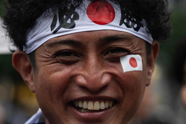 A fan smiles as he celebrates early in the morning at Shibuya crossing in Tokyo on June 15, 2026, after Japans 2-2 draw with the Netherlands in the World Cup. (Photo by Andrew CABALLERO-REYNOLDS / AFP)