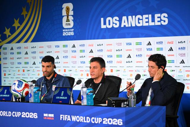 Iran's head coach Amir Ghalenoei (C) gives a press conference next to Iran’s forward #09 Mehdi Taremi (L) at Los Angeles Stadium in Inglewood on June 14, 2026, on the eve of the 2026 World Cup football match between Iran and New Zealand. (Photo by Patrick T. FALLON / AFP)