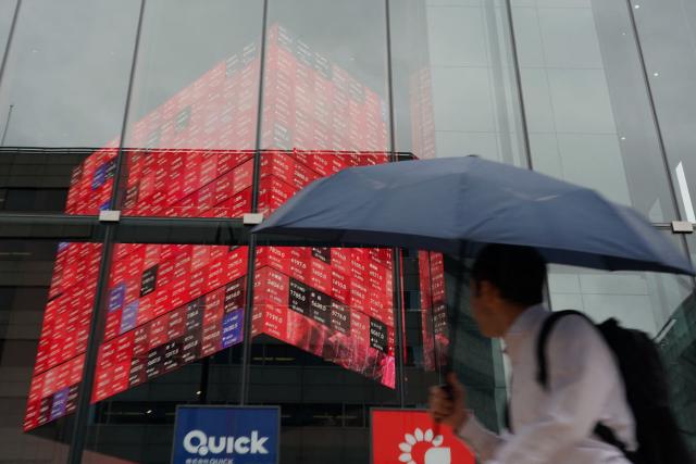 A man walks in front of an electronic quotation board displaying the Nikkei 225 stock prices on the Tokyo Stock Exchange in Tokyo on June 15, 2026. (Photo by Kazuhiro NOGI / AFP)