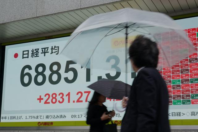 Pedestrians walk past an electronic quotation board displaying the Nikkei Stock Average on the Tokyo Stock Exchange in Tokyo on June 15, 2026. (Photo by Kazuhiro NOGI / AFP)