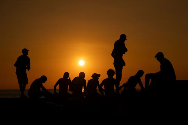 Youngsters sit at the Malecon in Havana at sunset on June 14, 2026. (Photo by YAMIL LAGE / AFP)