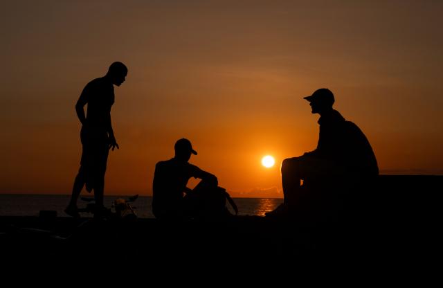 Men sit at the Malecon in Havana at sunset on June 14, 2026. (Photo by YAMIL LAGE / AFP)