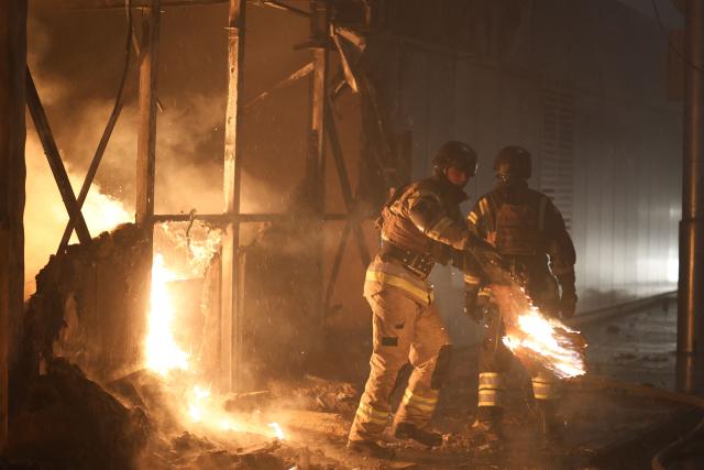 Firefighters put out a blaze at a market during the Russian missile strike on the Ukrainian capital of Kyiv on June 15, 2026, amid the Russian invasion in Ukraine. A major missile attack struck Kyiv early on June 15, an AFP reporter witnessed, with projectiles intercepted in the sky and glowing debris falling onto the city. Ukrainian officials including the city's mayor Vitali Klitschko reported on Telegram that strikes hit various districts. (Photo by Serhii Okunev / AFP)