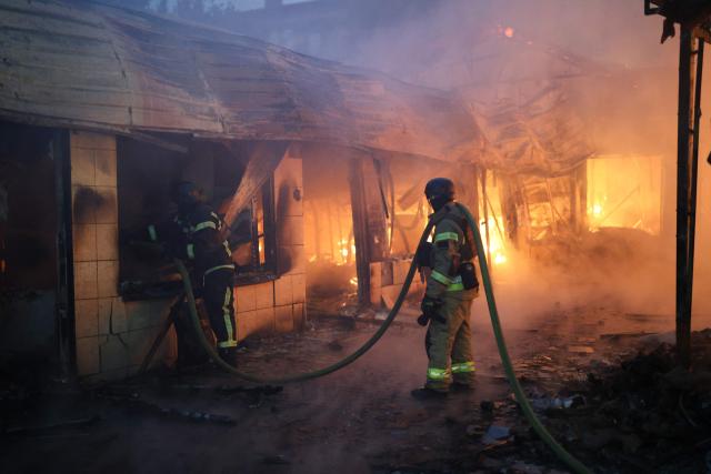 Firefighters put out a blaze at a market during the Russian missile strike on the Ukrainian capital of Kyiv on June 15, 2026, amid the Russian invasion in Ukraine. A major missile attack struck Kyiv early on June 15, an AFP reporter witnessed, with projectiles intercepted in the sky and glowing debris falling onto the city. Ukrainian officials including the city's mayor Vitali Klitschko reported on Telegram that strikes hit various districts. (Photo by Serhii Okunev / AFP)